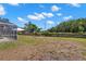 Large, flat backyard with mature trees, a wooden fence, and a glimpse of the screened-in pool area at 490 Knight Dr, Tarpon Springs, FL 34688