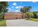 Charming single-story home featuring a well-manicured lawn, mature trees, and a three-car garage at 490 Knight Dr, Tarpon Springs, FL 34688