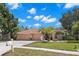 Charming single-story home featuring a well-manicured lawn, mature trees, and a three-car garage at 490 Knight Dr, Tarpon Springs, FL 34688