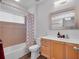 Bright bathroom featuring wood cabinets, a tub with a shower, and neutral decor at 5507 Keeler Oak St, Lithia, FL 33547