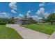 Stunning exterior of the house, featuring a large driveway, lush green lawn, and tropical landscaping at 5507 Keeler Oak St, Lithia, FL 33547