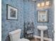 Stylish powder room with unique wallpaper, pedestal sink, and decorative mirror and shelving unit at 5507 Keeler Oak St, Lithia, FL 33547