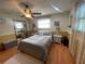 Comfortable bedroom with a ceiling fan, hardwood flooring, large mirror, and decoratively styled lamps on the nightstands at 6073 115Th N Ave, Pinellas Park, FL 33782