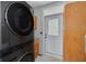 Functional laundry room with a modern washer/dryer, natural wood cabinets, and a door to the outside at 6904 S Fitzgerald St, Tampa, FL 33616