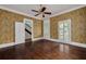 Charming living room featuring hardwood floors, floral wallpaper, and access to the backyard at 6904 S Fitzgerald St, Tampa, FL 33616