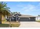 Charming single-story home featuring a three-car garage, a landscaped yard, and a stately palm tree at 7606 Nottinghill Sky Dr, Apollo Beach, FL 33572