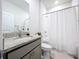Well-lit bathroom features a vanity with granite countertop and tiled shower with white shower curtain at 8214 Wheat Stone Dr, Zephyrhills, FL 33540