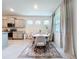 Bright dining area featuring a wood table, six chairs, stylish rug, and natural light from three windows at 8214 Wheat Stone Dr, Zephyrhills, FL 33540