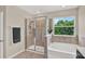 Bathroom featuring a stand-up shower, soaking tub, and large sunny windows with green outside view at 10379 Bridgegate Heights Loop, San Antonio, FL 33576