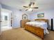 Bright bedroom featuring wooden bed, dresser, ceiling fan, neutral carpet and an attached bathroom at 10520 Tapestry Dr, Port Richey, FL 34668