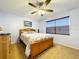 Comfortable bedroom features a wooden bed frame, ceiling fan, dresser and natural light through the window at 10520 Tapestry Dr, Port Richey, FL 34668