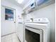 Laundry room with a door to the backyard, tile floors, storage shelf and modern washer and dryer at 10520 Tapestry Dr, Port Richey, FL 34668
