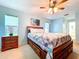 Cozy primary bedroom featuring a large bed with a quilt, side tables, and a ceiling fan at 10520 Tapestry Dr, Port Richey, FL 34668