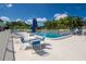 Community pool with a white fence, surrounded by tables, chairs, and tropical landscaping at 11200 102Nd Ave # 62, Seminole, FL 33778