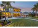Backyard at dusk featuring a pool with fire bowls, manicured lawn, and palm tree at 11327 Lake Lucaya Dr, Riverview, FL 33579