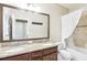 Bathroom featuring a double vanity with granite countertop, decorative mirror, and a shower with a white curtain at 11327 Lake Lucaya Dr, Riverview, FL 33579