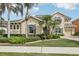 Elegant stucco home with a manicured lawn, lush landscaping, and palm trees at 11327 Lake Lucaya Dr, Riverview, FL 33579