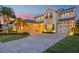Elegant two-story home with a paver driveway, lush landscaping, and a welcoming entrance at dusk at 11327 Lake Lucaya Dr, Riverview, FL 33579