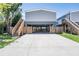 Home with elevated construction, featuring a large concrete driveway and wooden stairs at 13039 Keel Ct, Hudson, FL 34667