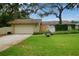 Inviting single-Gathering home with a well-manicured lawn, quaint bench, and attached garage at 13878 Oak Forest N Blvd, Seminole, FL 33776