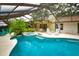 Private screened-in pool and spa with lush landscaping and outdoor seating offer a tranquil retreat at 13878 Oak Forest N Blvd, Seminole, FL 33776