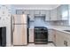 Well-equipped kitchen featuring stainless steel appliances, gray cabinetry, and clean white countertops at 15100 Avalon Ave, Clearwater, FL 33760