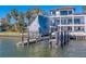 View of boat lift with boat covered in tarp and multi-story waterfront home at 15805 Redington Dr, Redington Beach, FL 33708