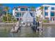 View of boat lift with boat covered in tarp and multi-story waterfront home at 15805 Redington Dr, Redington Beach, FL 33708