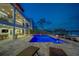Stunning backyard featuring a modern pool, spa, and waterfront views at twilight at 15805 Redington Dr, Redington Beach, FL 33708