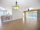 Spacious living room with tiled floors, decorative chandelier, and sliding door to screened in patio at 16142 Amethyst Key Dr, Wimauma, FL 33598