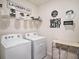Well-organized laundry room featuring a washer, dryer, shelving, and decorative laundry-themed decor at 17012 Oval Rum Dr, Wimauma, FL 33598
