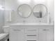 Bright bathroom featuring double vanity with round mirrors, white cabinets, and ample counter space at 1813 Hillside Dr, Tampa, FL 33610