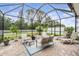 Screened-in patio with comfortable seating, lush greenery, and clear skies, perfect for relaxing outdoors at 19608 Lonesome Pine Dr, Land O Lakes, FL 34638