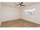 Light-filled bedroom with modern ceiling fan, hardwood flooring, and a view of the greenery outdoors at 2146 Waterside Dr, Clearwater, FL 33764