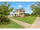 Charming two-story home featuring a lush green lawn, mature trees, and inviting walkway at 241 72Nd N St, St Petersburg, FL 33710