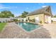 A private pool with a brick paver deck is surrounded by a white fence and lush landscaping at 241 72Nd N St, St Petersburg, FL 33710