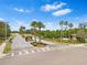 Community entrance featuring a gated entry, palm trees, and well-maintained landscaping at 2641 Big Pine Dr, Holiday, FL 34691