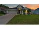 Charming single-story home at sunset with manicured lawn and beautiful landscaping, including young palm trees at 2641 Big Pine Dr, Holiday, FL 34691