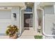 Close-up of a front door with decorative plants, a welcome mat, and a textured exterior wall at 2641 Big Pine Dr, Holiday, FL 34691