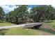 Scenic exterior view with a bridge over a stream leading to a charming home surrounded by mature trees at 3350 Stonebridge Trl, Valrico, FL 33596