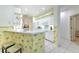 Bright kitchen with white cabinets and countertop, accented by unique palm tree-themed wallpaper and bar stool seating at 3350 Stonebridge Trl, Valrico, FL 33596