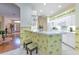 Bright kitchen with a breakfast bar featuring palm tree-themed wallpaper, bar stool seating, and white cabinets and appliances at 3350 Stonebridge Trl, Valrico, FL 33596