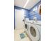 The laundry room has modern machines, tile floors and a blue wall and door at 34447 Blue Ash Ct, Wesley Chapel, FL 33545