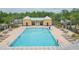 Large rectangular community pool with lounge chairs, tables and gated access with a yellow pool house at 34447 Blue Ash Ct, Wesley Chapel, FL 33545
