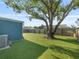 Spacious backyard featuring a mature shade tree, artificial turf, and a privacy fence at 4238 Glissade Dr, New Port Richey, FL 34652