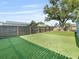 A manicured backyard featuring an artificial lawn, a privacy fence, and blue sky at 4238 Glissade Dr, New Port Richey, FL 34652