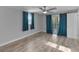 Bright bedroom with light wood floor, ceiling fan, blue curtains, and sliding glass door at 4238 Glissade Dr, New Port Richey, FL 34652