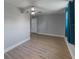 Empty staged bedroom with wood floor, ceiling fan, blue curtains, and view into the hallway at 4238 Glissade Dr, New Port Richey, FL 34652