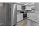 Well-lit kitchen with stainless steel appliances, gray countertops, light wood floor and white cabinets at 4238 Glissade Dr, New Port Richey, FL 34652