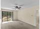 Bedroom featuring carpet, ceiling fan and sliding door access to a screened-in pool and spa at 495 Appaloosa Rd, Tarpon Springs, FL 34688